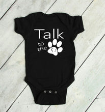 Load image into Gallery viewer, Black baby onesie with 'Talk to the Paw' text on a light wooden floor.