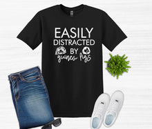 Load image into Gallery viewer, Black t-shirt with 'Easily Distracted by Guinea Figs' text, paired with jeans, sneakers, and sunglasses on a white background.