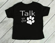 Load image into Gallery viewer, Black t-shirt with 'Talk to the paw' text on a wooden floor