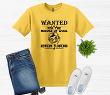 Load image into Gallery viewer, A yellow graphic t-shirt featuring a black 'WANTED' poster design for 'Woolse Misuse', styled in a flat-lay with blue jeans, white sneakers, sunglasses, and a small green plant on a white wood background.