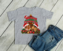 Load image into Gallery viewer, A heather gray toddler t shirt with a festive Christmas graphic featuring two guinea pigs in Santa hats and the text 'Wheeking Around the Christmas Tree', laid flat on a light gray wood plank background.