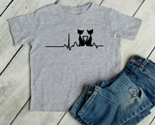 Load image into Gallery viewer, Gray t-shirt with black cat design and heartbeat line on a wooden surface with jeans.