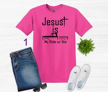 Load image into Gallery viewer, Pink t-shirt with 'Jesus is my ride or die' text, paired with jeans, sneakers, and sunglasses on a white background.