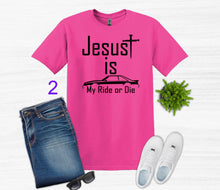 Load image into Gallery viewer, Pink t-shirt with 'Jesus is my ride or die' text, paired with jeans, sneakers, and sunglasses on a white background.