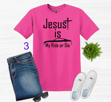 Load image into Gallery viewer, Pink t-shirt with 'Jesus is my ride or die' text, paired with jeans, sneakers, and sunglasses on a white background.