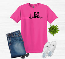 Load image into Gallery viewer, Pink t-shirt with a black cat heartbeat design, paired with jeans, white sneakers, and sunglasses on a light gray background.