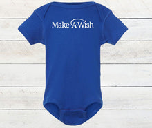 Load image into Gallery viewer, A royal blue short-sleeve baby bodysuit with 'Make A Wish' printed in white across the chest, displayed flat against a light whitewashed wood plank background.
