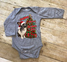 Load image into Gallery viewer, A heather gray long-sleeve baby bodysuit laid flat on a rustic wooden surface. The front features a graphic print of a rabbit wearing a Santa hat next to a Christmas tree with the text 'Hopping Around the Christmas Tree'.