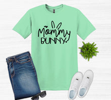 Load image into Gallery viewer, Mint green t-shirt with 'Mommy Bunny' text, blue jeans, white sneakers, sunglasses on a white background.