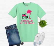 Load image into Gallery viewer, Green t-shirt with 'Chinchillin' at the Beach' design, blue jeans, white sneakers, and sunglasses on a white background.