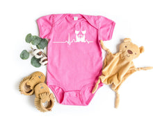 Load image into Gallery viewer, Pink baby bodysuit with a cat heart design, surrounded by baby booties and a plush toy on a white background.