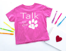Load image into Gallery viewer, Pink t-shirt with 'Talk to the paw' design on a white background with markers and a heart.