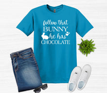 Load image into Gallery viewer, Blue t-shirt with text, jeans, white sneakers, sunglasses, and a small plant on a light gray background
