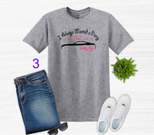 Load image into Gallery viewer, Gray t-shirt with graphic design, blue jeans, white sneakers, and sunglasses on a light gray background.