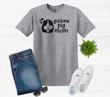Load image into Gallery viewer, Gray t-shirt with 'guinea pig mom' text and graphic, paired with jeans, sneakers, and sunglasses on a white background.