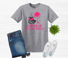 Load image into Gallery viewer, Gray t-shirt with 'Chinchillin' at the Beach' design, blue jeans, white sneakers, and sunglasses on a light gray background.