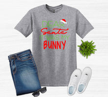 Load image into Gallery viewer, Gray t-shirt with Christmas-themed text, jeans, sneakers, and sunglasses on a white background