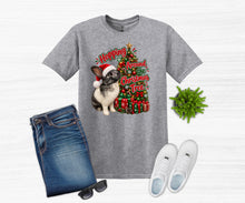 Load image into Gallery viewer, A heather gray graphic t-shirt featuring a rabbit and Christmas tree design, styled in a flat lay with blue jeans, white sneakers, sunglasses, and a small green plant on a white wood-textured background.