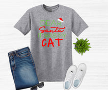 Load image into Gallery viewer, Gray t-shirt with 'Dear Santa, it was my cat' text, blue jeans, white sneakers, and sunglasses on a white background.