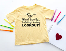Load image into Gallery viewer, Yellow t-shirt with text and graphic on a white surface with markers and a heart.