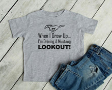 Load image into Gallery viewer, Gray t-shirt with Mustang graphic and text on a wooden surface with jeans.