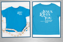 Load image into Gallery viewer, Two blue t-shirts with 'Jesus Loves You' text on a white wooden background