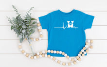 Load image into Gallery viewer, Blue t shirt with a cat heart rate design on a white wooden surface with decorative elements.