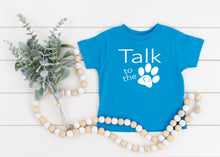 Load image into Gallery viewer, Blue t shirt with 'Talk to the paw' text on a white wooden surface with decorative elements.