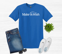 Load image into Gallery viewer, A blue short-sleeve T-shirt with 'Make-A-Wish' printed in white across the chest, styled in a flat lay with folded blue jeans, white sneakers, sunglasses, and a small green plant on a light wood background.